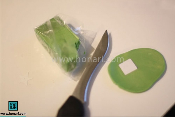 آموزش گوشواره خمیری با طرح فرفره-مرحله 2 مقداری از خمیر را جدا کرده ، آنرا با استفاده از وردنه صاف میکنیم و سپس به شکل مربع برش میزنیم