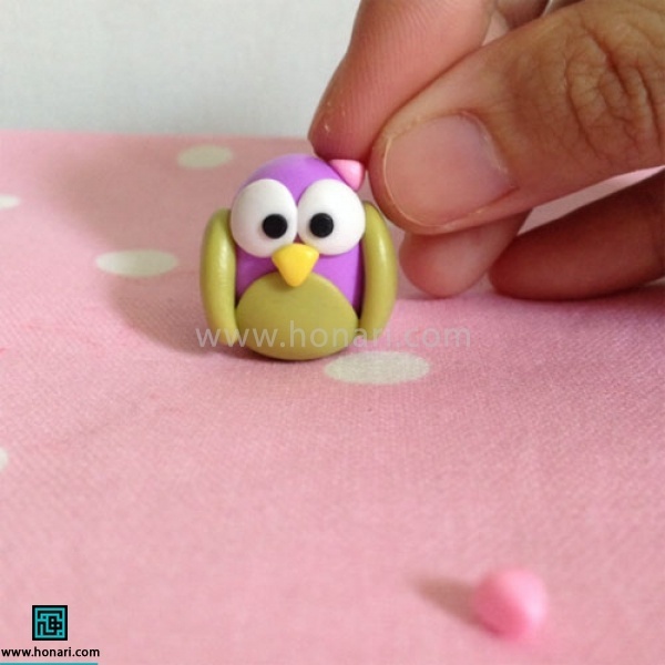 آموزش عروسک خمیری جغد-مرحله 16 سپس با استفاده از خمیر صورتی دو مثلت کوچک به عنوان شاخ درست کرده و روی سر جغد قرار میدهیم