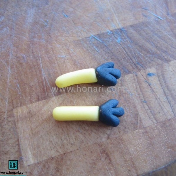 آموزش عروسک خمیری مینیون-مرحله 17 سپس دو دایره مشکی درست کرده با استفاده از قلم سر گرد حالت انگشت را روی آن درست میکنیم و به دست ها متصل میکنیم