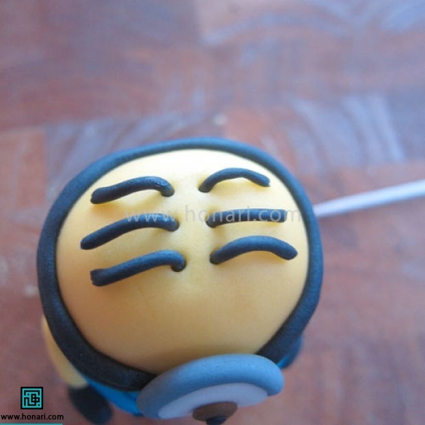 آموزش عروسک خمیری مینیون-مرحله 23 با خلال دندان سوراخ های کوچکی روی سر ایجاد کرده ، رول هایی که درست کرده ایم را به عنوان مو داخل آنها قرار میدهیم