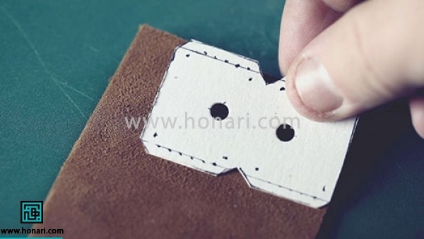 اموزش دوخت کاور چرمی کلید-مرحله 1 مواد و ابزار اولیه مورد نیاز برای شروع آموزش چرم دوزی : اشبالت مصنوعی واتر جت قهوه ای ، حلقه کلید پرس ، مدبر جاسوئیچی ، نخ موم زده ، خودکار ژله ای ، خط کش ، سوراخ کن دستی ، کاتر سربی برای ساخت این کاور چرمی کلید ابتدا الگو رو روی چرم قرار می دیم و ترسیمش می کنیم.