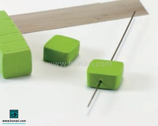 گردنبند مهره ای-مرحله 3 برای ساخت مهره های مکعبی هم ابتدا یک استوانه به قطر یک سانتی متر می سازیم بعد با کمک ابزار تختی که در دسترس داریم اطراف اون رو فشار می دیم تا به صورت یک مکعب مستطیل صاف با مقطع مربع به شکلی که در تصویر می بینید در بیاد. بعد اون رو به قطعات هفت میلی متری برش می زنیم و سوزن رو از داخل مهره ها رد می کنیم.