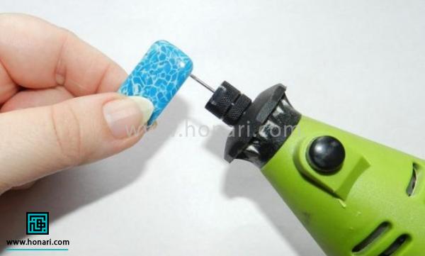 آموزش ساخت دستبند از خمیر فیمو با طرح فیروزه-مرحله 7 با مته ی دستی محل عبور نخ دستبند یا کش نامرئی را سوراخ می کنیم. این کار را قبل از خشک شدن خمیر با استفاده از یک سورن بلند هم می توانیم انجام دهیم.