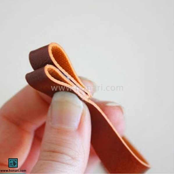 اموزش تل سر چرم دوزی پاپیون-مرحله 2 از ابتدای نوار شروع به تا کردن میکنیم. اولی را بزرگتر و دومی را کوچکتر تا میکنیم