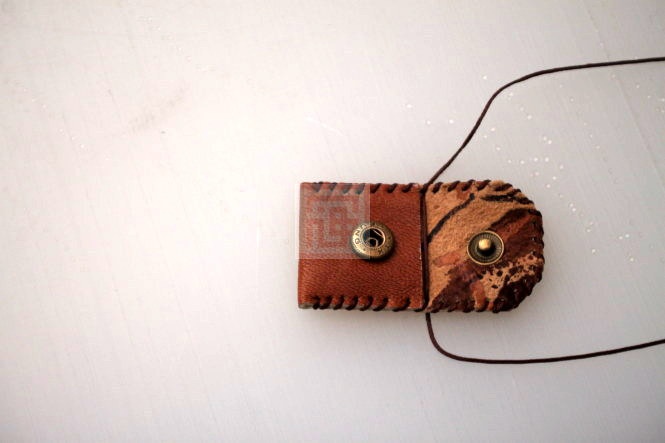 با نخ موم زده حلقه ای درست کنید و آنرا از سوراخ های دو طرف کیف عبور داده بهم گره بزنید.