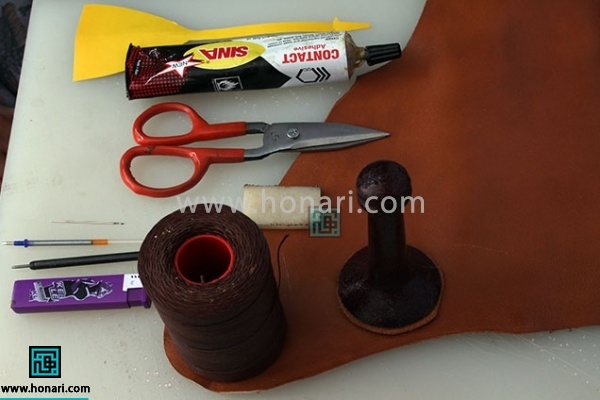 اموزش ساخت سرکلیدی چرمی زرافه-مرحله 1 1.مواد و ابزار اولیه مورد نیاز برای شروع آموزش چرم دوزی : چرم بزی قهوه ای ، حلقه کلید پرس زنجیردار ، نخ موم زده قهوه ای ، تخته کار ایرانی ، چسب آهن ، کرپ قهوه ای مشته بزرگ ، خودکار ژله ای ، سمبه سایز یک ونیم ، سوزن بزرگ ، قیچی مخصوص چرم ، فندک فشاری