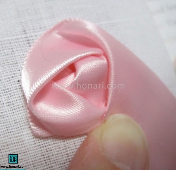 دوباره با دست روبان را دور روبان قبلی بپیچیدو با نخ سوزن به پارچه محکم کنید