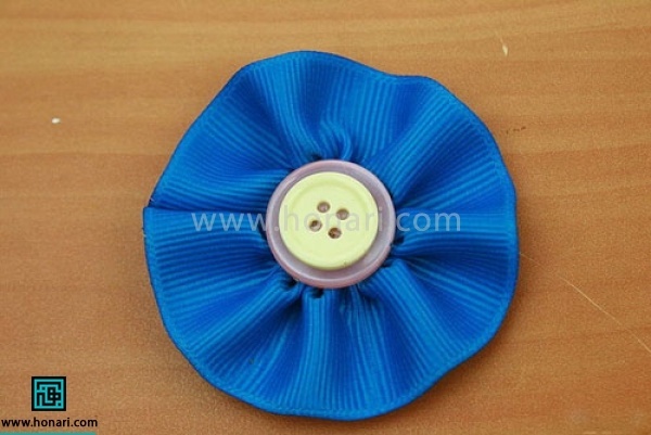 یک دکمه را با چسب تفنگی روی گل بچسبانید و اجازه بدهید خشک بشود