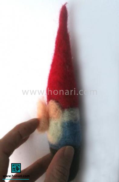 با توجه به آموزش عکس ، بینی عروسک را در سر جای خود در صورت قرار میدهیم . 