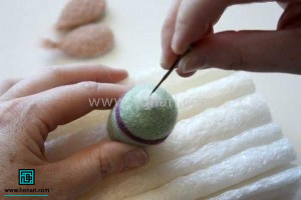 مقداری الیاف سفید برای چشم ها برداشته کف دست بصورت توپک کوچکی در اورده و بر روی بدن جای چشم ها با سوزن زدن ثابت کنید.