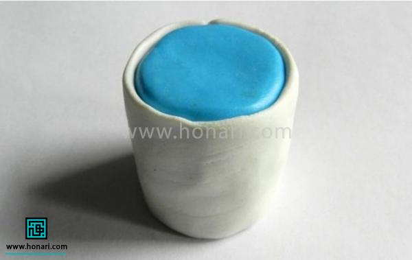 یک لایه ی نازک از خمیر فیمو سفید رنگ دور استوانه ی آبی می کشیم.