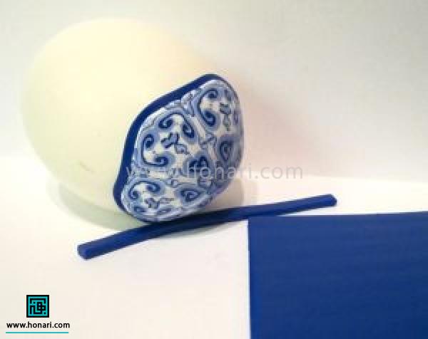 شش ضلعی رو در انتهای تخم مرغ میگذاریم و با نوار باریکی از رنگ قالب خمیر( دراینجا آبی تیره)یک نوار باریک دور تا دور لبه ی شش ضلعی ایجاد می کنیم.